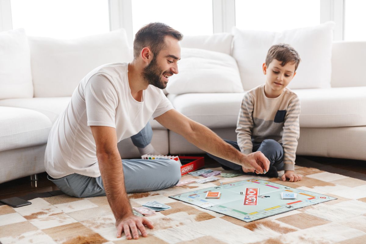 Un père et son fils jouant au Monopoly sur le tapis