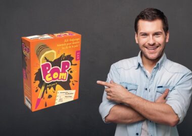 Un homme souriant pointant vers une boîte de jeu de société Pop Corn