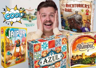 Un homme souriant entouré de boîtes de jeux de société comme Jaipur, Azul et Les Aventuriers du Rail.